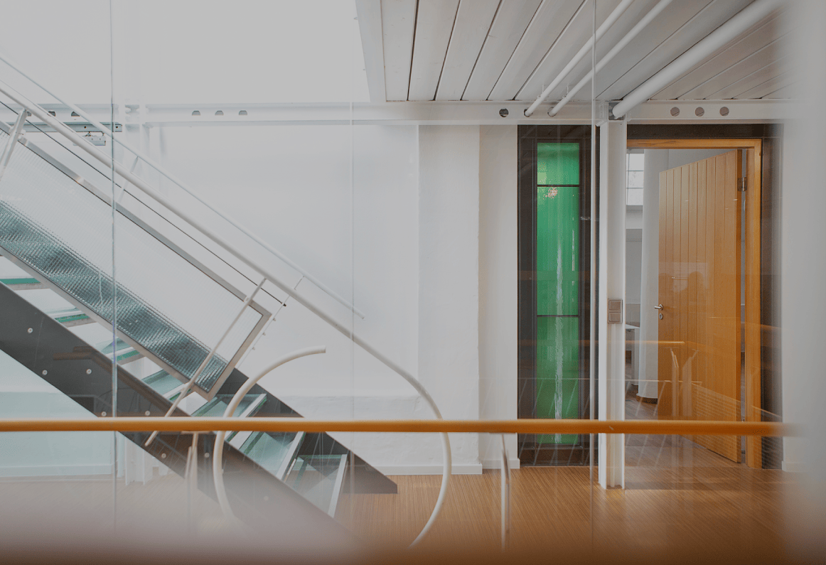 Heller Büroflur mit moderner Glas- und Metalltreppe