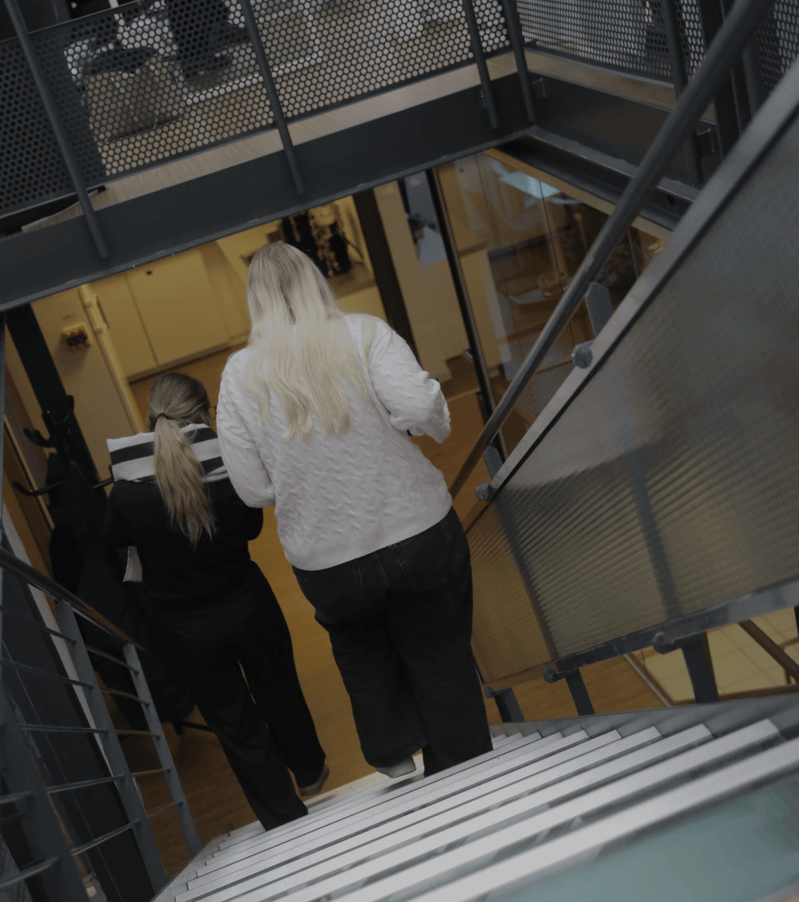 Zwei Personen gehen eine Treppe in einem modernen Bürogebäude hinunter
