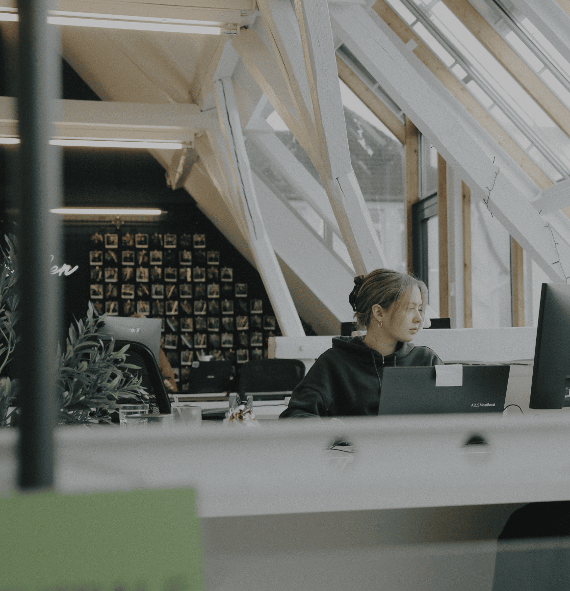 Person arbeitet konzentriert an einem Laptop in einem hellen Büro mit Dachfenstern