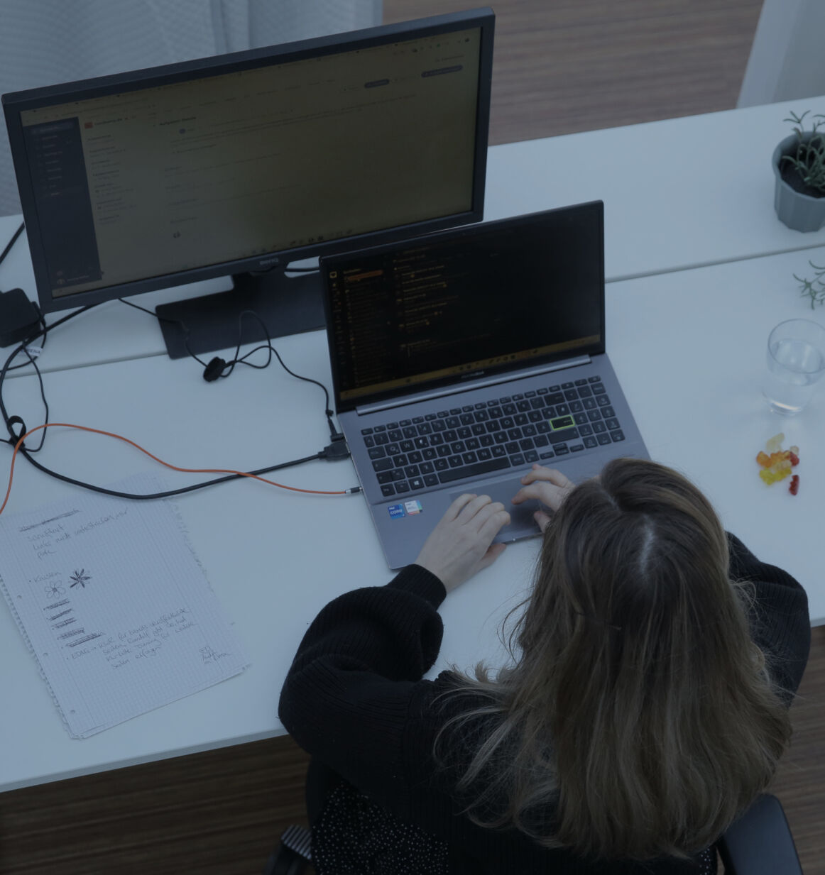 Person tippt an einem Laptop am Schreibtisch im Büro, aufgenommen aus der Vogelperspektive