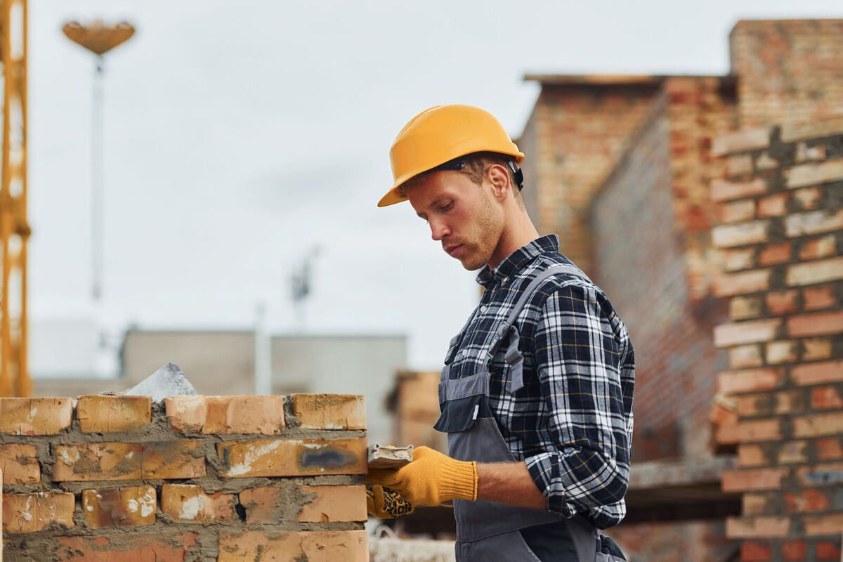 Maurer mit gelbem Helm arbeitet auf der Baustelle