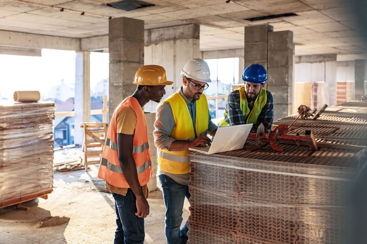 Bauteam prüft die Lohnabrechnung am Laptop auf der Baustelle