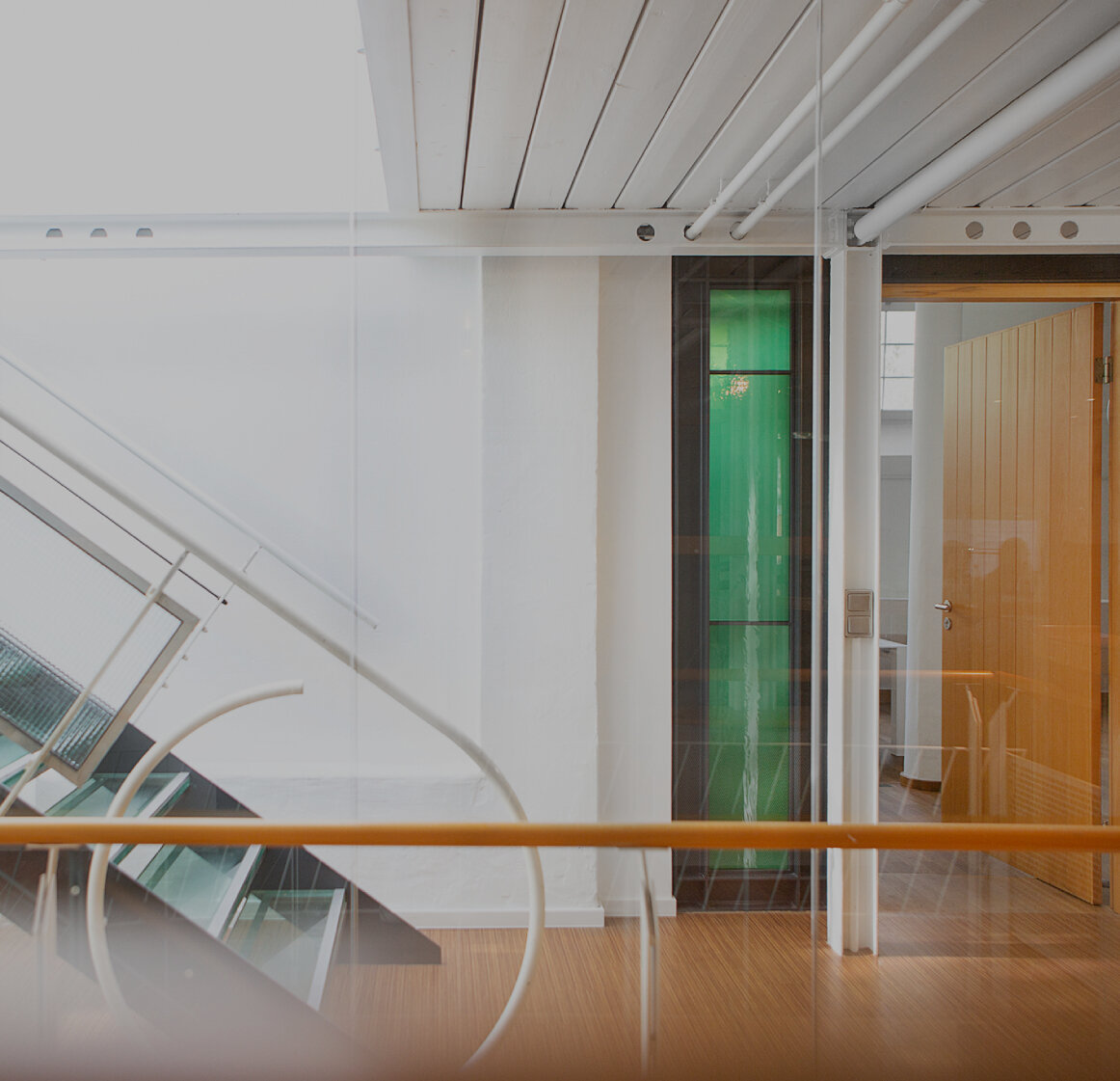 Heller Büroflur mit moderner Glas- und Metalltreppe, weißen Wänden und Holzboden