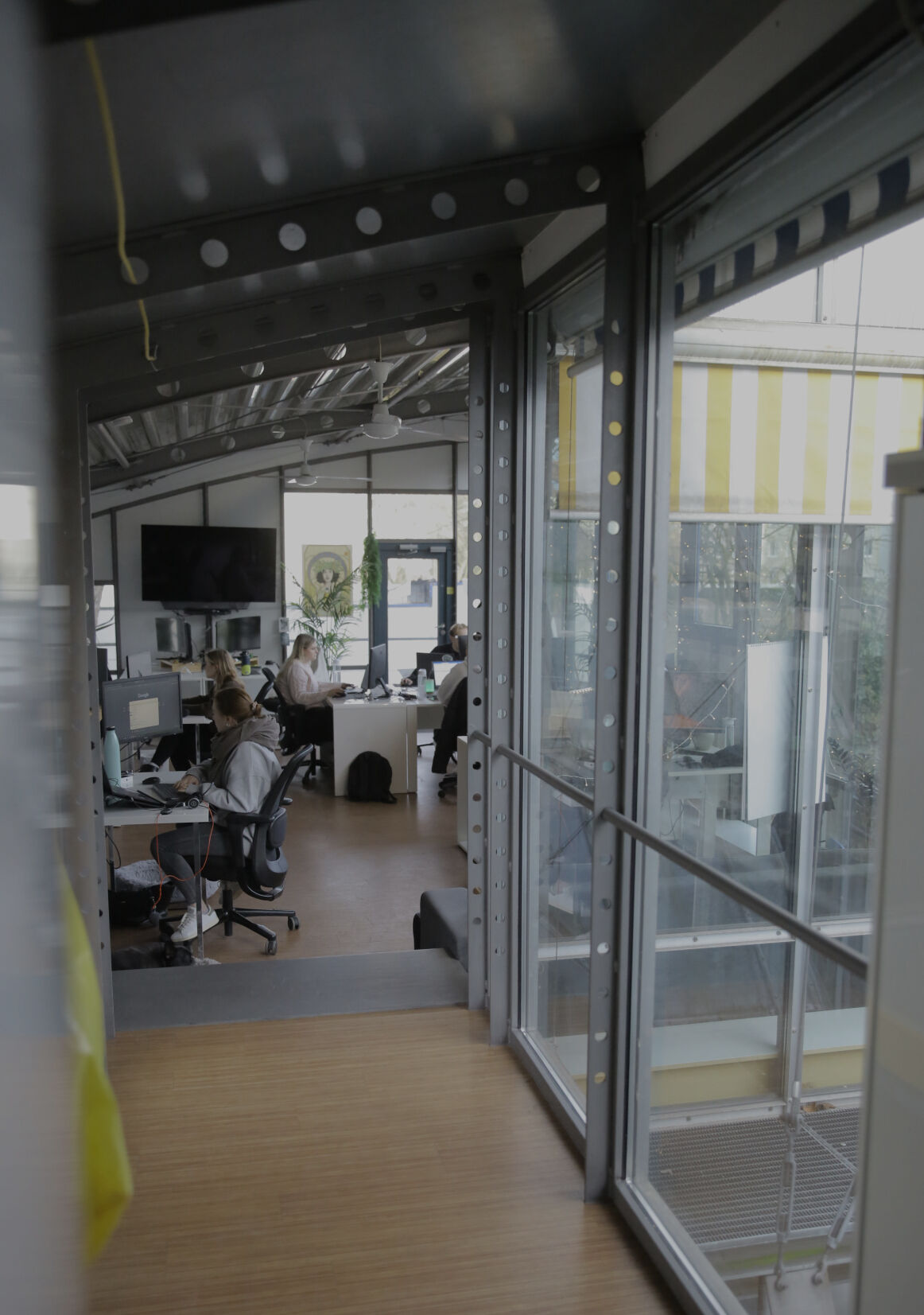 Blick durch eine Glaswand in ein Büro, in dem mehrere Personen an Schreibtischen arbeiten