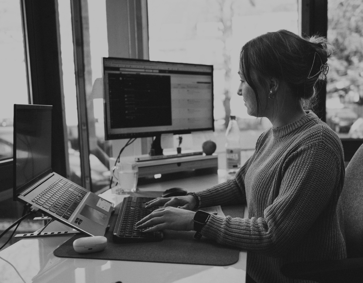 Junge Frau sitzt an einem Schreibtisch im modernen Büro und arbeitet konzentriert