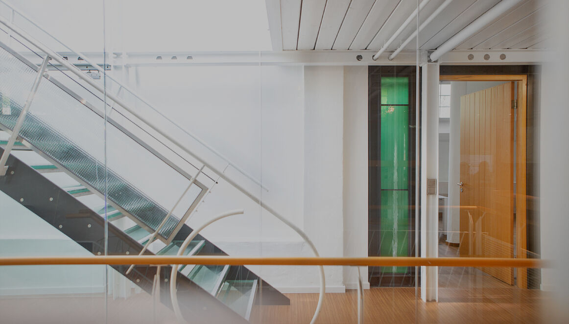 Heller Büroflur mit moderner Glas- und Metalltreppe und Holzboden