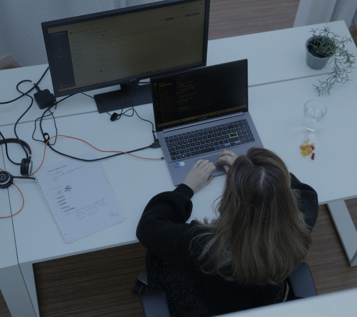 Person tippt an einem Laptop am Schreibtisch, Vogelperspektive mit externem Monitor